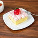 A piece of cake on a CAC Garden State square porcelain plate with a strawberry on top.