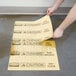 A person using a yellow Rubbermaid spill absorbent pad to cover a spill on the floor in a grocery store aisle.