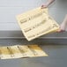 A person holding a yellow paper over a spill on the floor.