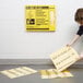 A woman using a Rubbermaid yellow absorbent pad to cover the floor.