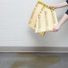 A person holding a yellow box of Rubbermaid yellow absorbent pads.