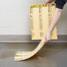 A person using a yellow Rubbermaid medium absorbent pad to clean up a spill.