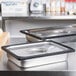 A stainless steel steam table pan with a black silicone band on a counter.