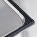 A close-up of a stainless steel steam table pan with a black silicone tray inside.