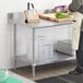 A man standing in front of a Regency stainless steel work table with undershelf.