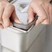 A person's hands using a grey rubber band to open a metal container.