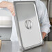 A person using a Vollrath gray silicone steam table pan band on a stainless steel pan.