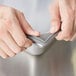 A person's hands opening a grey silicone pan band over a stainless steel surface.