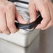 A person using a black Vollrath silicone band to hold a metal container.