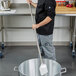 A man using a Carlisle Sparta paddle with a stainless steel handle to stir a large metal pot.