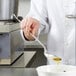 A chef pouring oil from a Vollrath hooked solid spoon into a bowl.