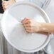 A person holding a silver Vollrath Arkadia stock pot cover.