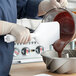 A person pouring chocolate into a bowl with a Carlisle white paddle.