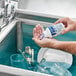 A person washing dishes in a sink with Edwards-Councilor Steramine Sanitizing Tablets on the counter.