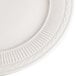 A close up of a 9 3/8" ivory china plate with an embossed rim.