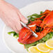 A hand using a Choice Double Jaw Lobster Cracker to cut a lobster.