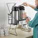 A man pouring coffee into a Choice 3-Piece Airpot Merchandising Rack Set on a counter in a hospital cafeteria.