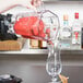 A person pouring a drink into a Waring blender jar on a counter.