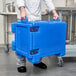 A man in a chef's uniform holding a blue Cambro Ultra Pan Carrier.