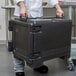 A person holding a black Cambro Ultra Pan Carrier.