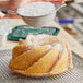 A person pouring Domino confectioners sugar on a cake.