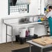 A man in blue gloves and an apron using a Regency soiled dish table to wash dishes in a professional kitchen.