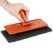 A person holding an orange 3M Doodlebug stripping pad.