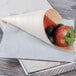 A Tablecraft small wooden serving cone filled with strawberries and grapes on a table.