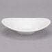 A white Reserve by Libbey Royal Rideau porcelain bowl with a curved edge on a gray surface.