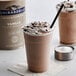 A cup of Ghirardelli Vanilla Frappe with whipped cream and chocolate chips on a counter.