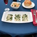 A white rectangular Arcoroc tray with food on it on a table.