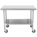 A silver metal Advance Tabco work table with wheels.