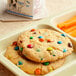 A tray of cookies and carrot sticks with M&M's Milk Chocolate Mini Baking Bits on top.