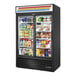 A True black refrigerated merchandiser with glass doors and shelves full of food.