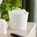A white disposable paper ice bucket filled with ice cubes.