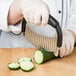 A person using a Tablecraft stainless steel crinkle cutter to slice a cucumber.