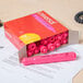 A Universal box of pink highlighters on a desk with a pink highlighter sitting on top.