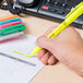 A hand holding a Universal Chisel Tip Pocket Highlighter writing on paper.