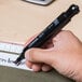 A hand holding a Universal black chisel tip permanent marker over a piece of paper.