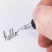 A hand writing "hello" with a black Universal One gel pen.