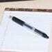 A Universal One black gel pen on a pad of paper.