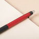 A Universal One red retractable ballpoint pen on a piece of paper.