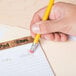 A hand holding a Universal yellow woodcase pencil over a piece of paper.