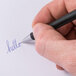 A hand writing "hello" on a piece of paper with a Universal One blue fine point pen.