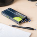 A box of Universal One blue fine point pens on a desk with one pen on a piece of paper.