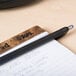 A Universal One blue fine point retractable pen lying on a piece of paper on a table.