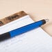 A Universal One blue retractable ballpoint pen on a notebook.