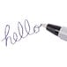 The tip of a Universal Economy black oil-based ballpoint pen writing on a white background.