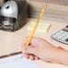 A hand holding a Universal One Blackstonian pencil and writing on a piece of paper.