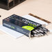 A box of Universal black medium point gel pens on a desk.
